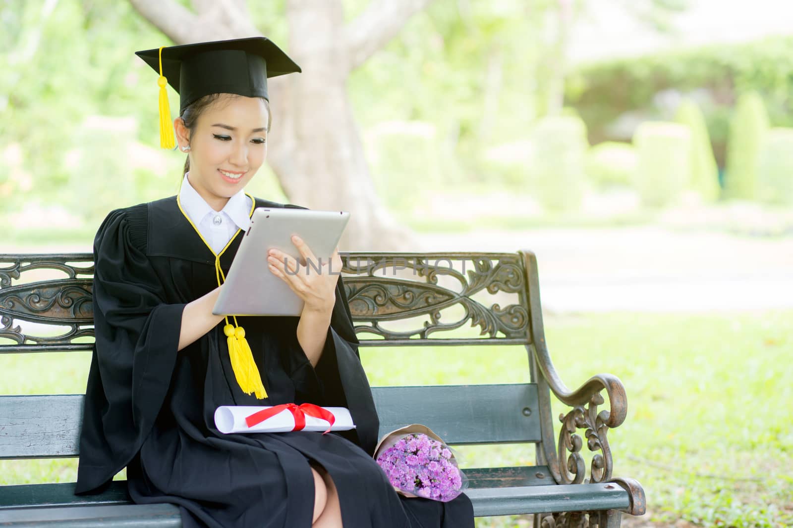 Graduate playing tablet in her hand feeling relaxing and so happiness in commencement day and search job new