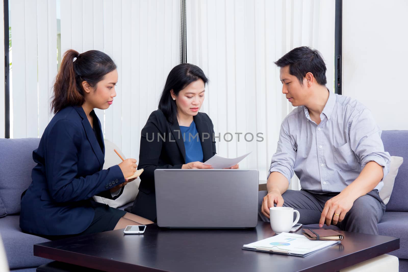 Team of business three people working together on a laptop with during a meeting sitting around a table.