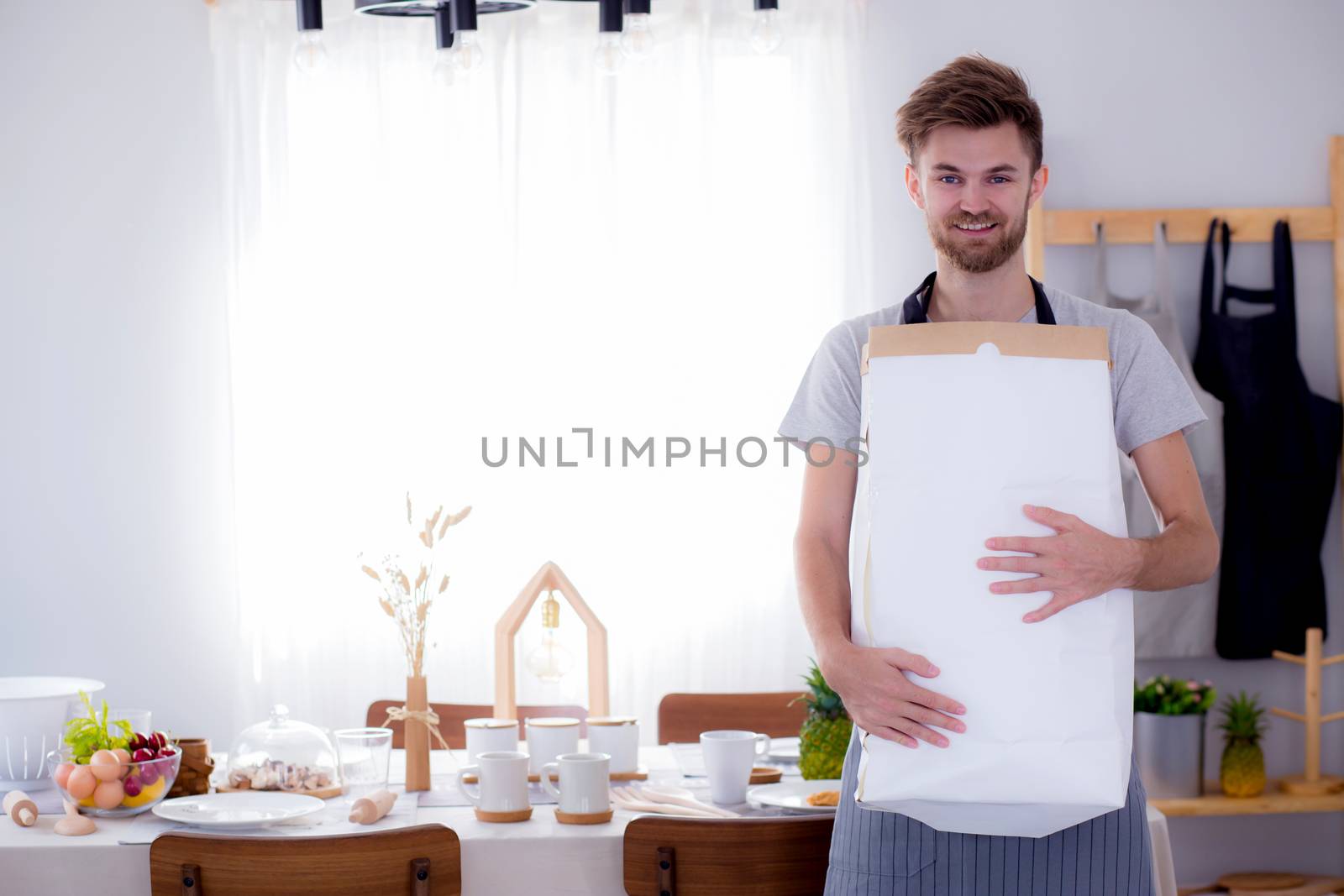 Portrait of a modern guy holding a paper bag with groceries.