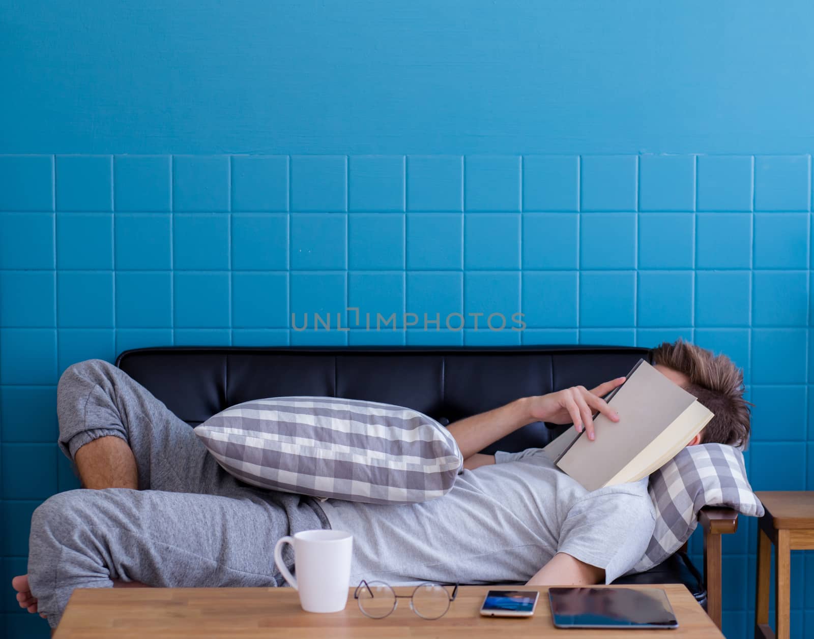 Man sleeping on old sofa with book covering his face because rea by nnudoo
