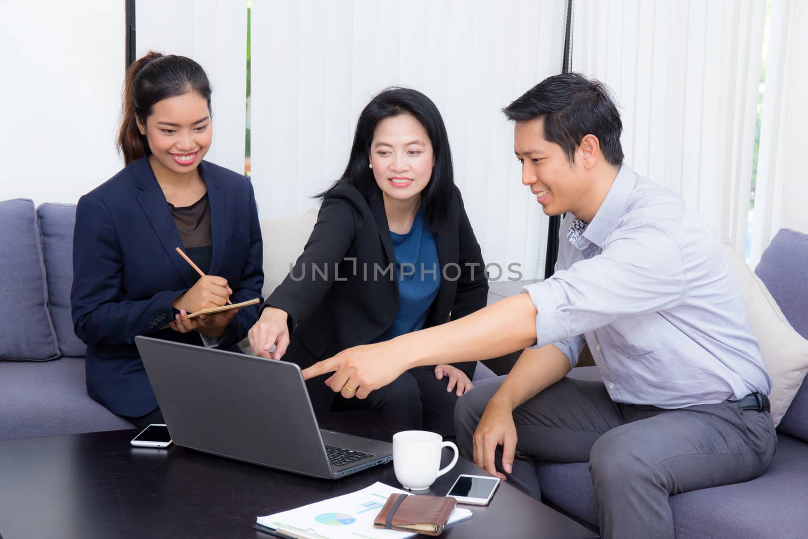 Team of business three people working together on a laptop with during a meeting sitting around a table.