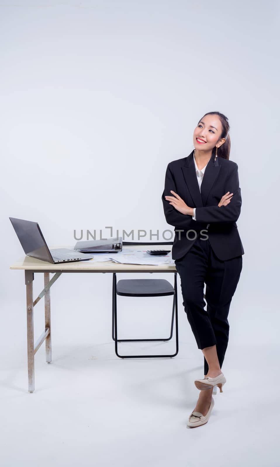 Confident businesswoman in office smiling at the camera with fol by nnudoo