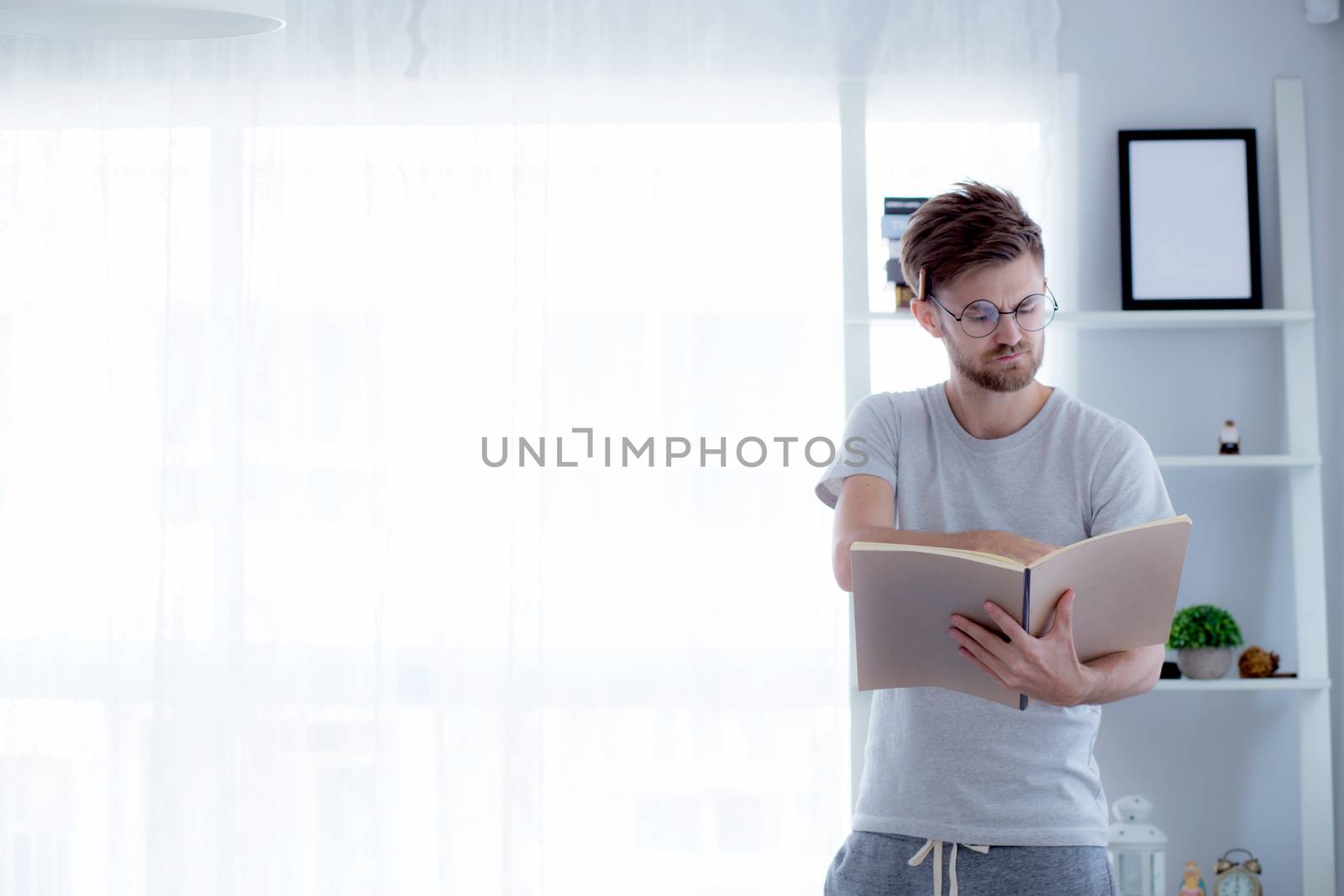 Handsome guy in eyeglasses is reading book preparing exam with s by nnudoo