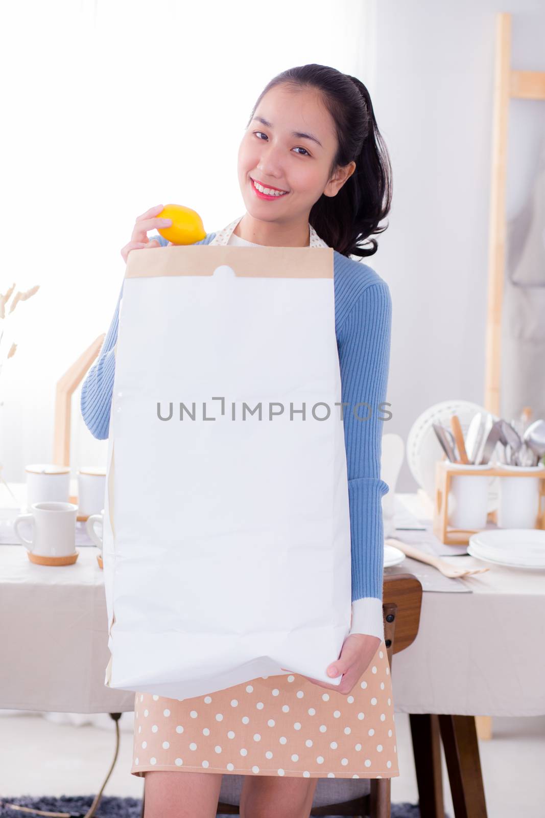 Portrait of a woman holding a paper bag with groceries. by nnudoo