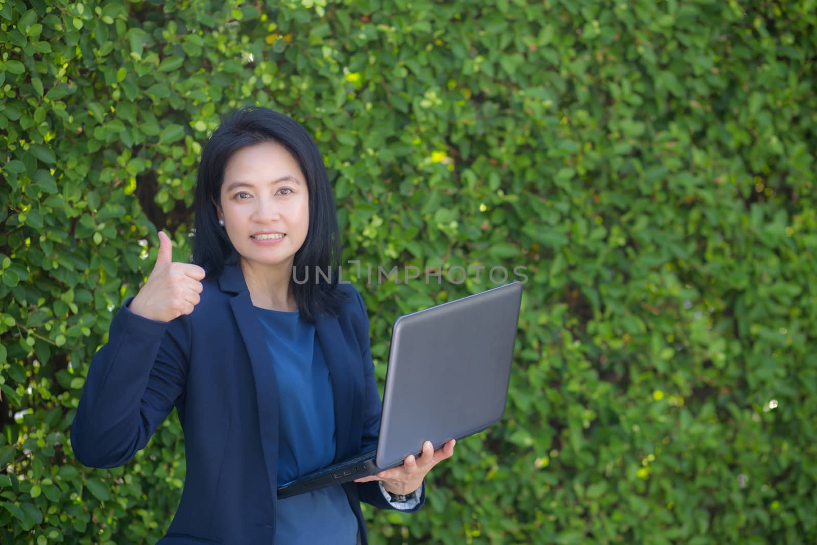 businesswoman holding computer notebook and showing thumb up making the ok gesture.
