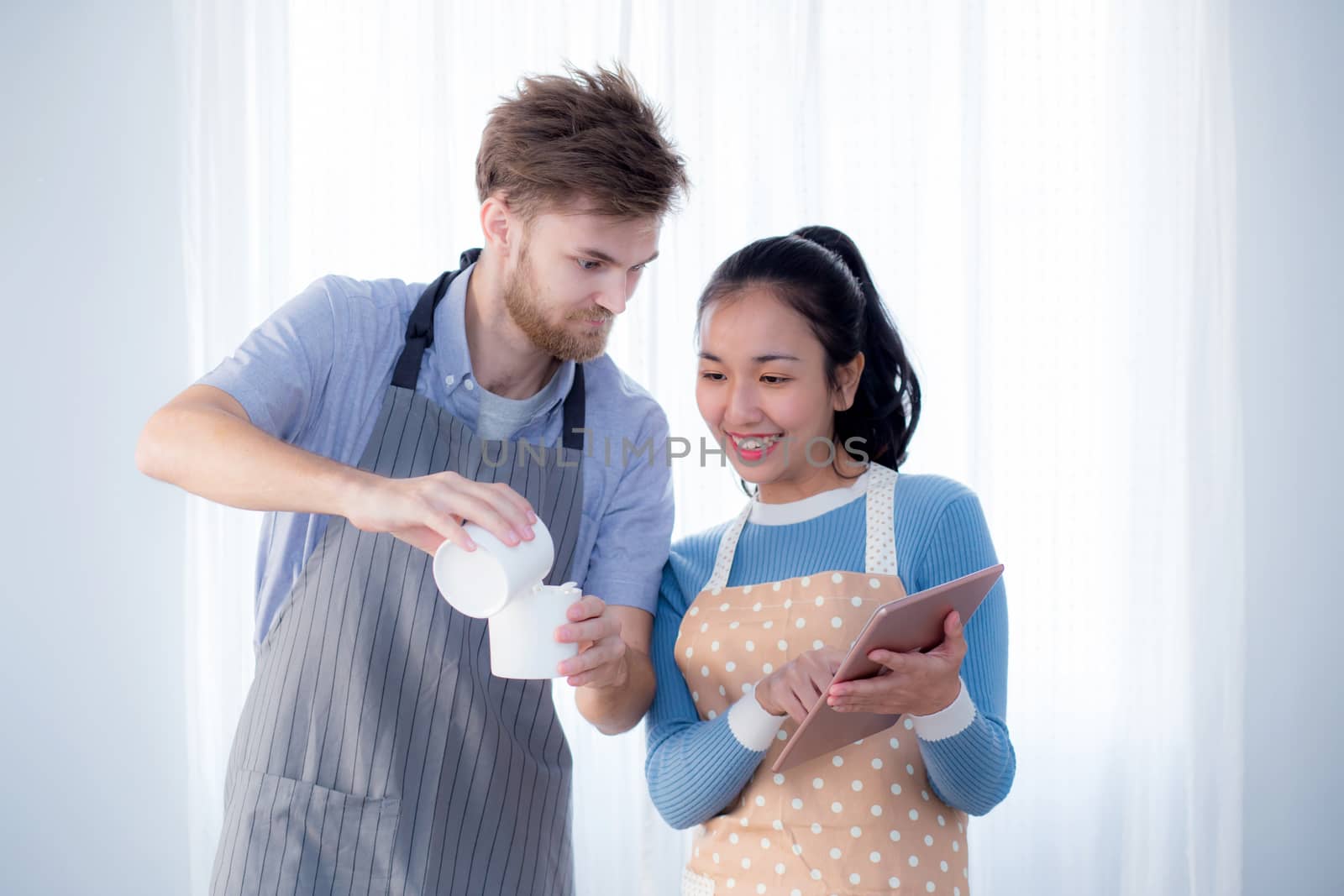 Couple in home kitchen using electronic tablet.