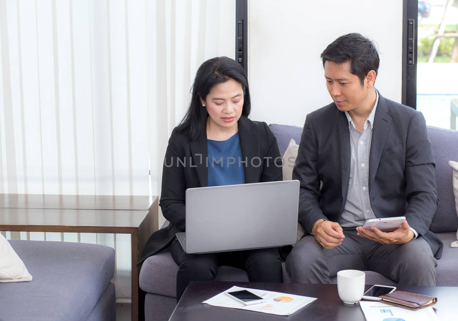 Team of business two people working together on a laptop with during a meeting sitting around a table.