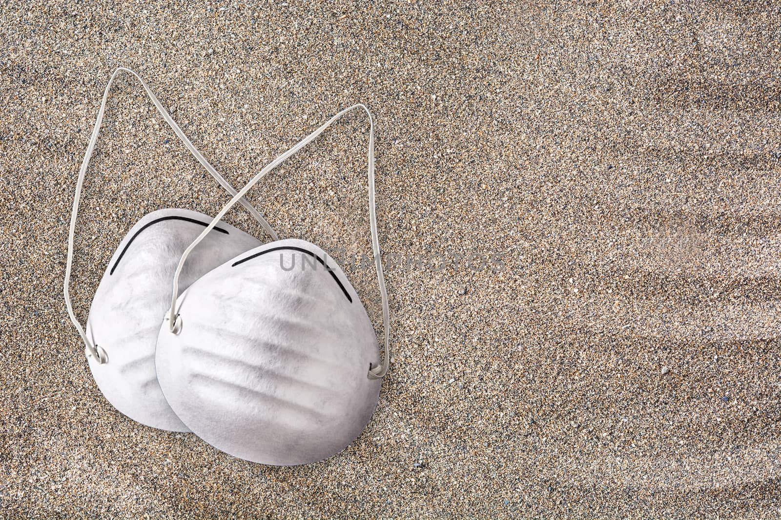 Medical protective mask on sand background