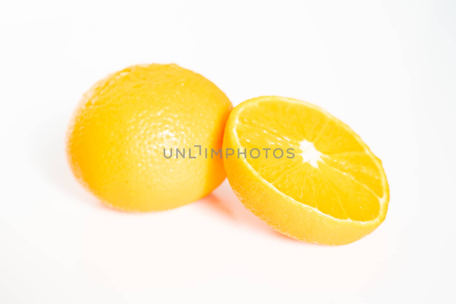 A whole orange and a half against a plain white background