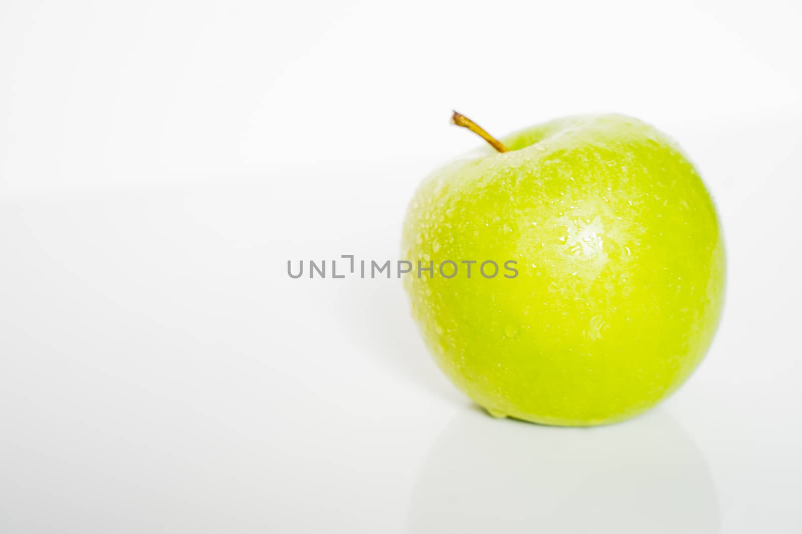 A whole granny smith green apple against a plain whit background