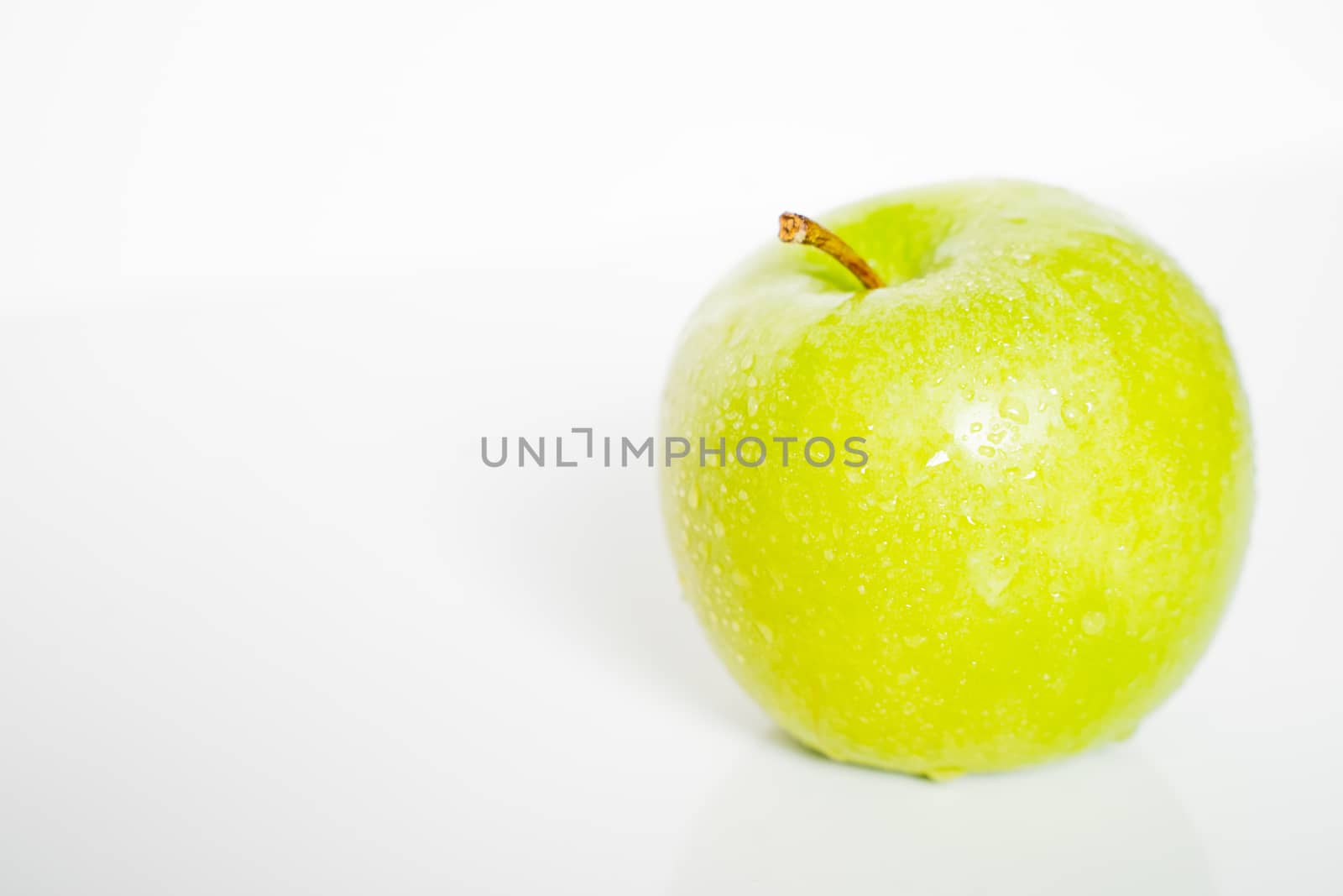 A whole granny smith green apple against a plain whit background