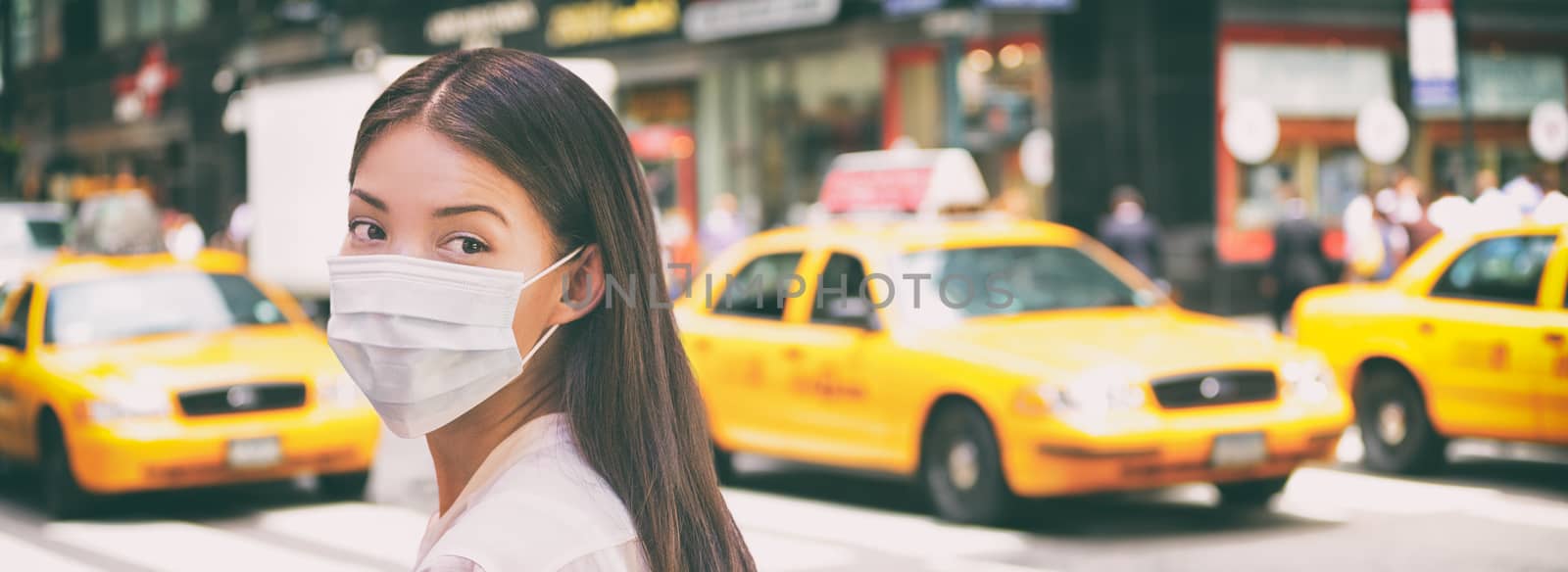 Corona virus travel ban China woman tourist walking in New York city street wearing surgical mask coronavirus protection, outbreak spreading scare. Panoramic banner background of traffic taxi cabs.