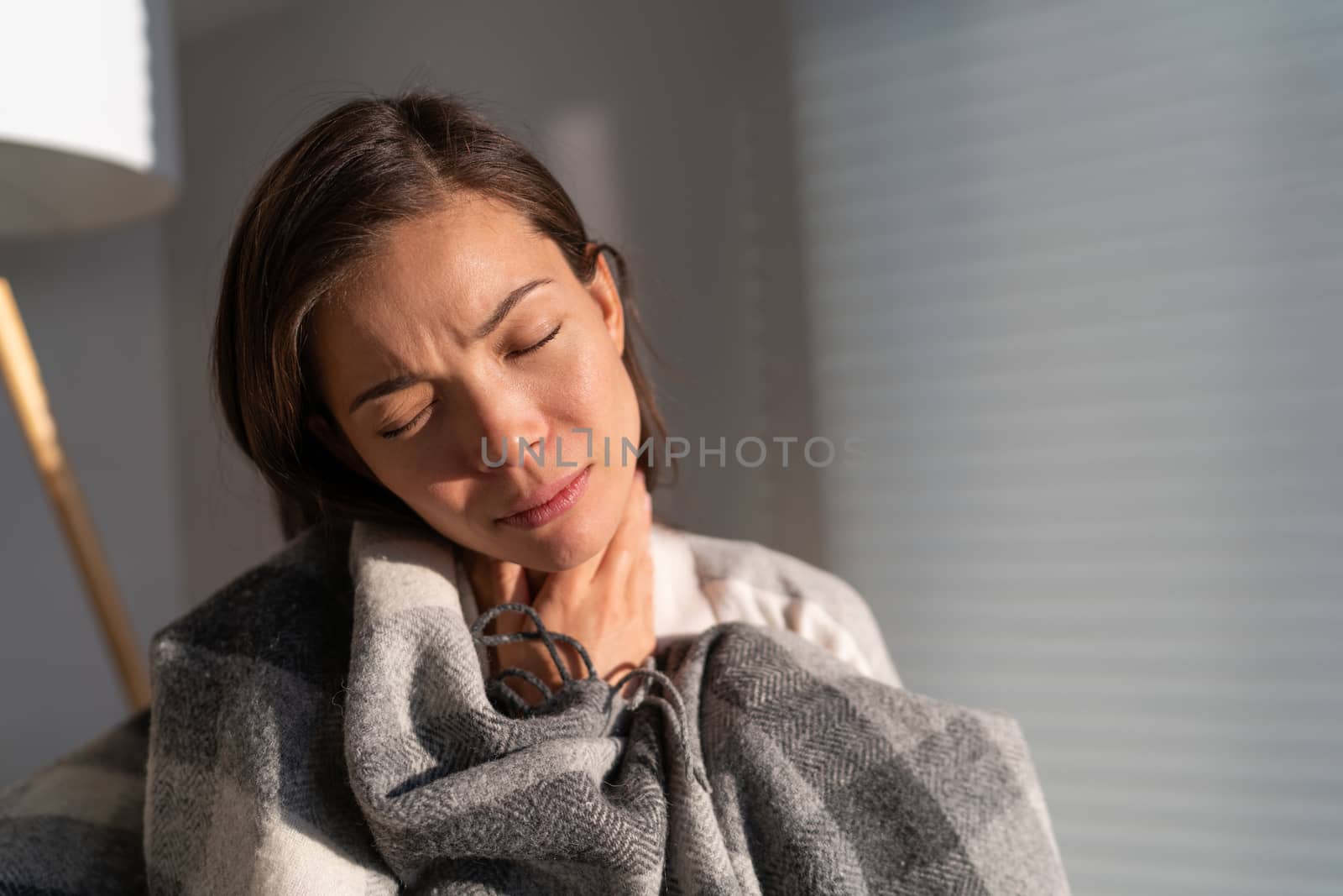 Coronavirus disease (COVID-19) symptoms are a runny nose, sore throat, cough, and fever. Corona virus illness can be more severe for some people. Asian woman with throat pain at home.