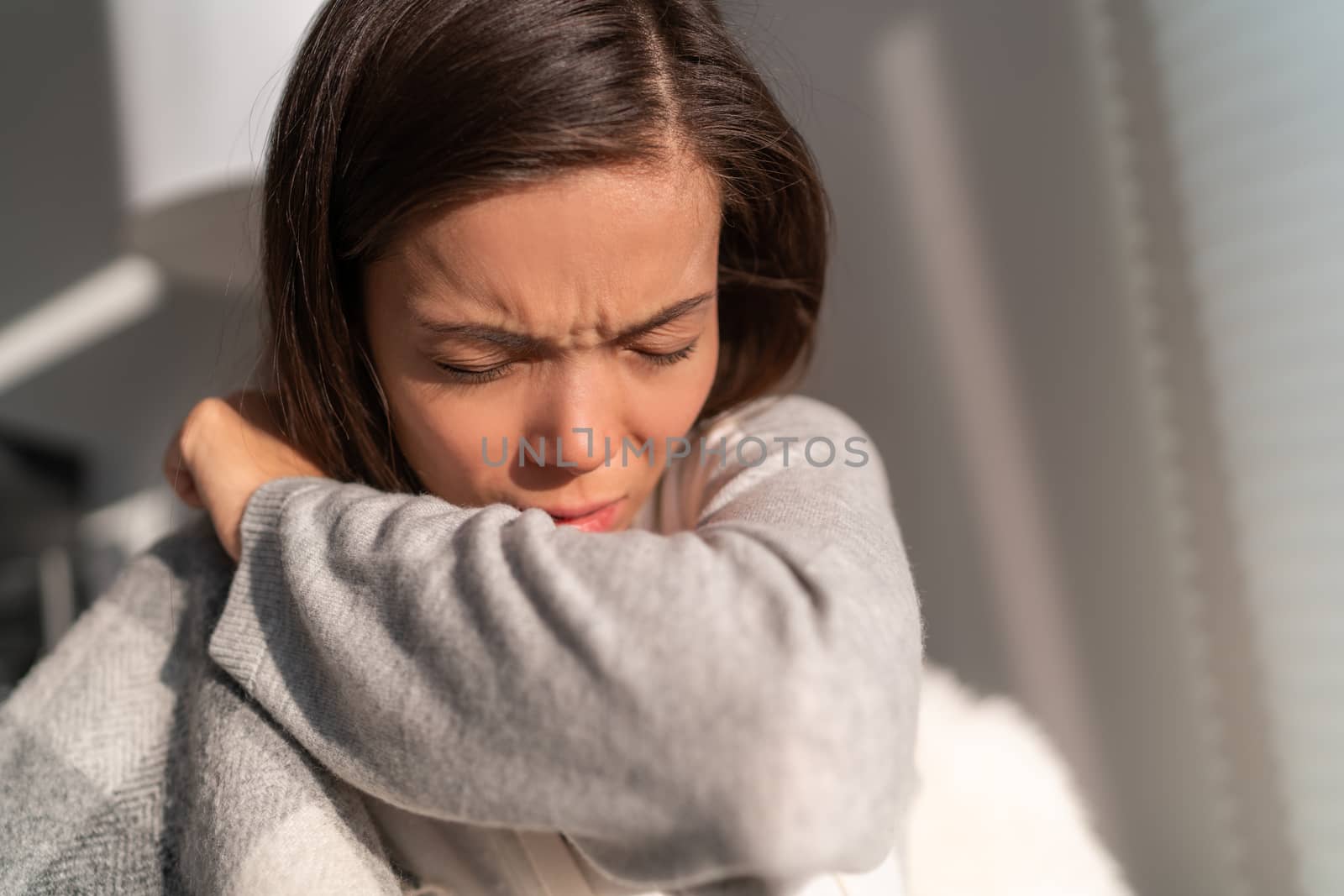 Coronavirus COVID-19 reducing of risk of spreading the infection by covering nose and mouth when coughing and sneezing with tissue or flexed elbow. Asian woman cough in arm prevention.