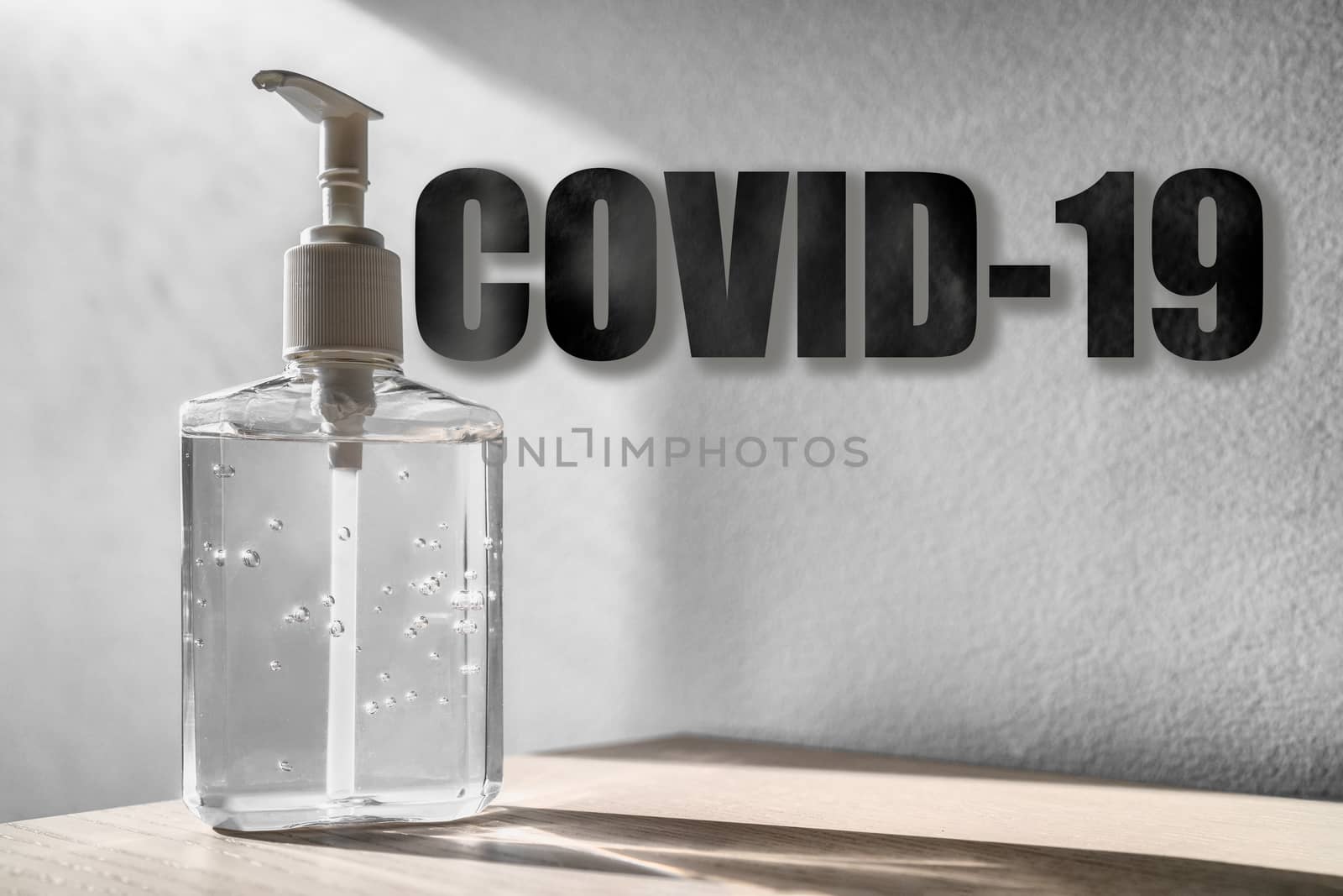 Coronavirus COVID-19 text title over hand sanitizer bottle background with texture.