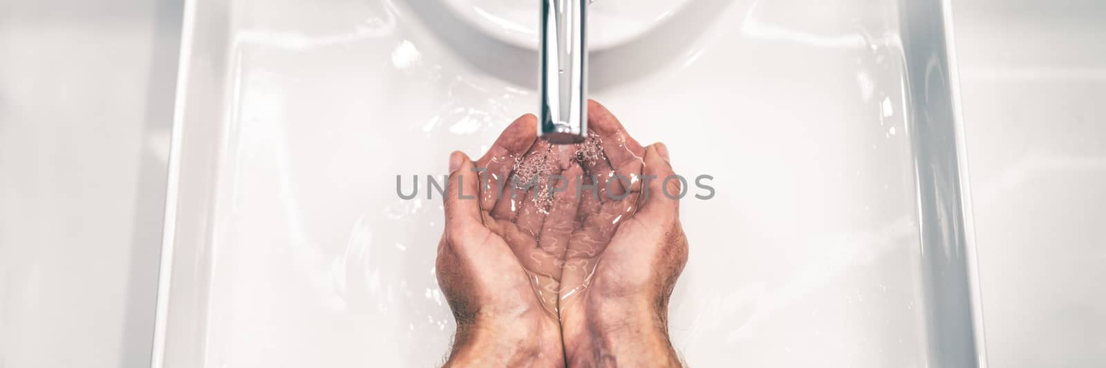 COVID-19 Coronavirus prevention washing hands with soap at bathroom sink man hand hygiene for corona virus pandemic precaution by washing hands frequently for 20 seconds. Panoramic banner by Maridav
