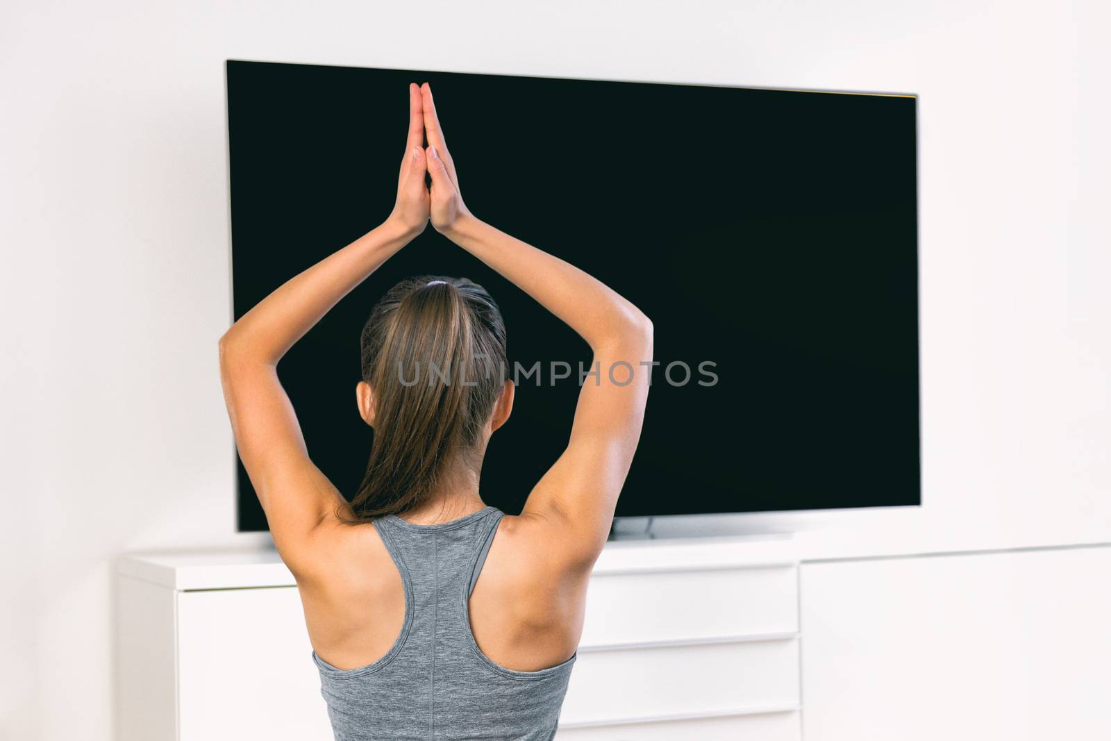 Tv yoga at home fitness class woman meditating stretching hands watching live streaming video class online of yogi teacher meditation wellness course by Maridav