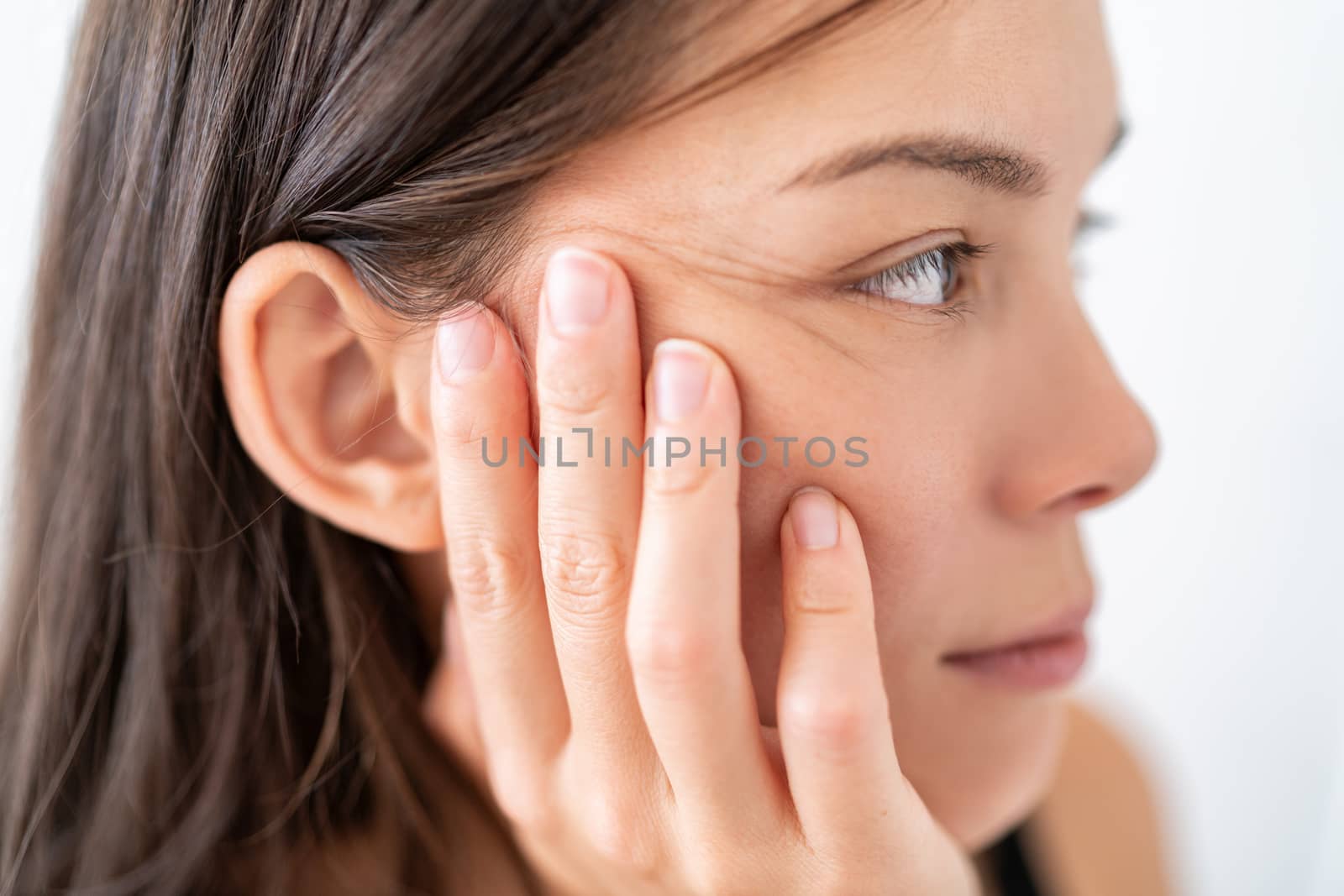 Coronavirus infection prevention CDC hygiene guidelines, wash hands frequently and refrain from touching face with hand. Asian woman resting on palm with fingers touching eyes, nose, mouth on cheek.
