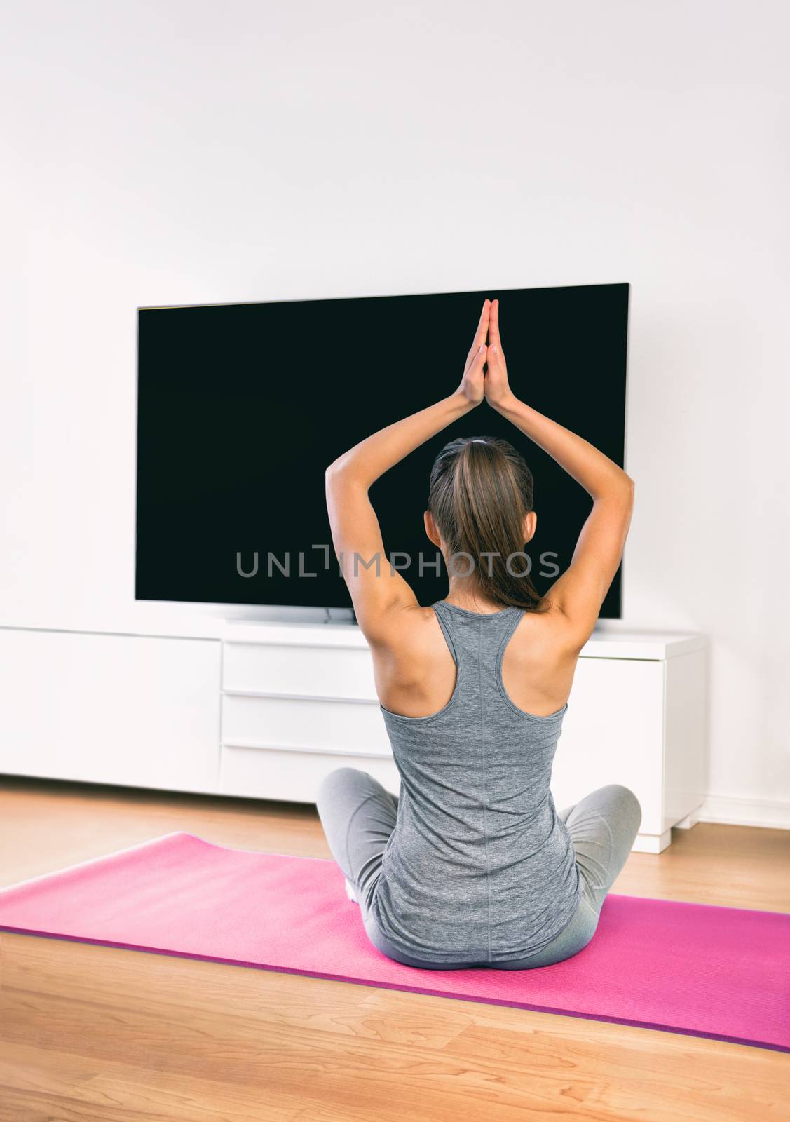 Home workout woman doing yoga mediation watching online app class on tv show. Home fitness healthy lifestyle exercises.