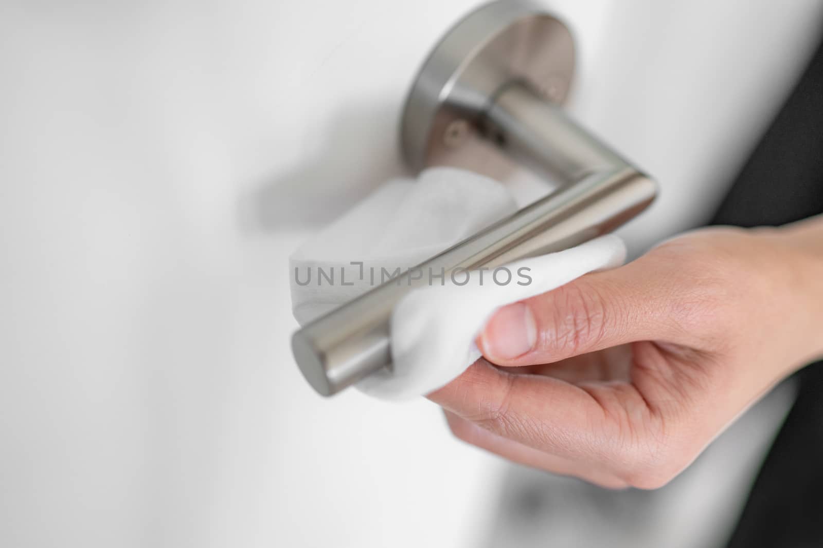 Coronavirus COVID-19 Prevention cleaning woman wiping doorknob with antibacterial disinfecting wipe for killing corona virus on touching surfaces, or touching public bathroom handle with tissue.