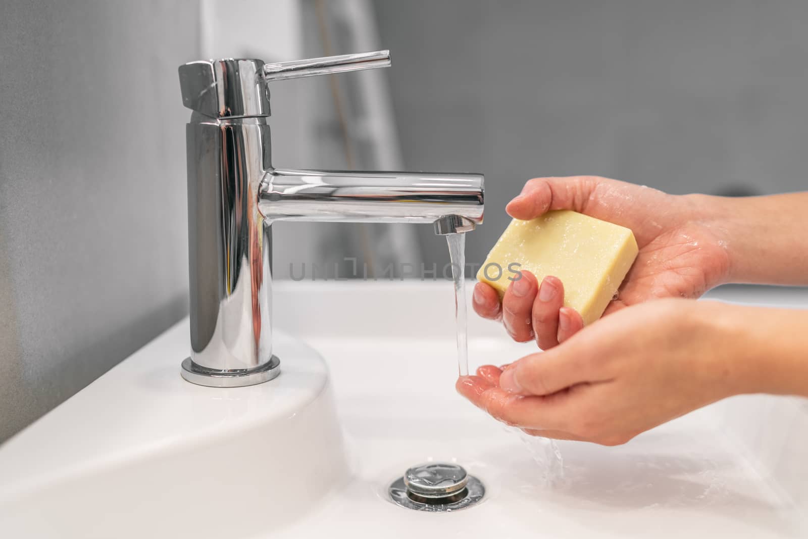 Washing hands with soap for 20 seconds hand hygiene woman holding bar of soap for COVID-19 corona virus prevention, to stop spreading coronavirus.