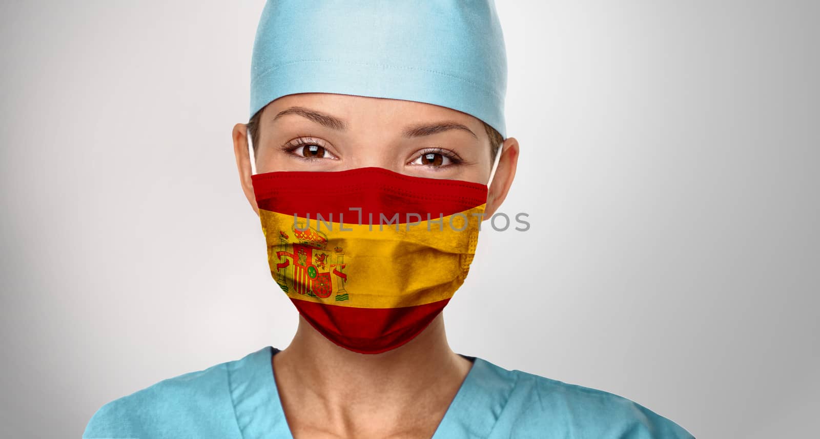 COVID-19 pandemic in Spain Asian doctor with spanish flag print on surgical mask. Happy confident woman medical nurse giving positivity. Coronavirus in Spain.