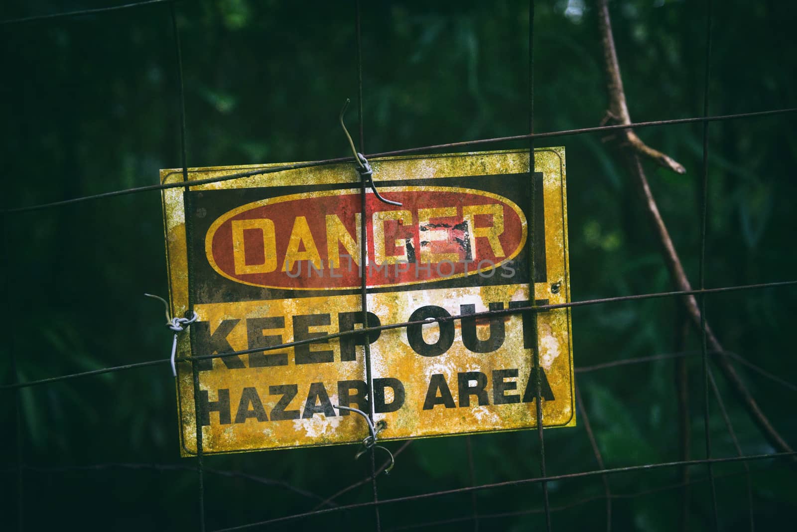 Danger sign with text KEEP OUT HAZARD AREA as warning message hanging on fenced dark zone, dirty poster outside by Maridav