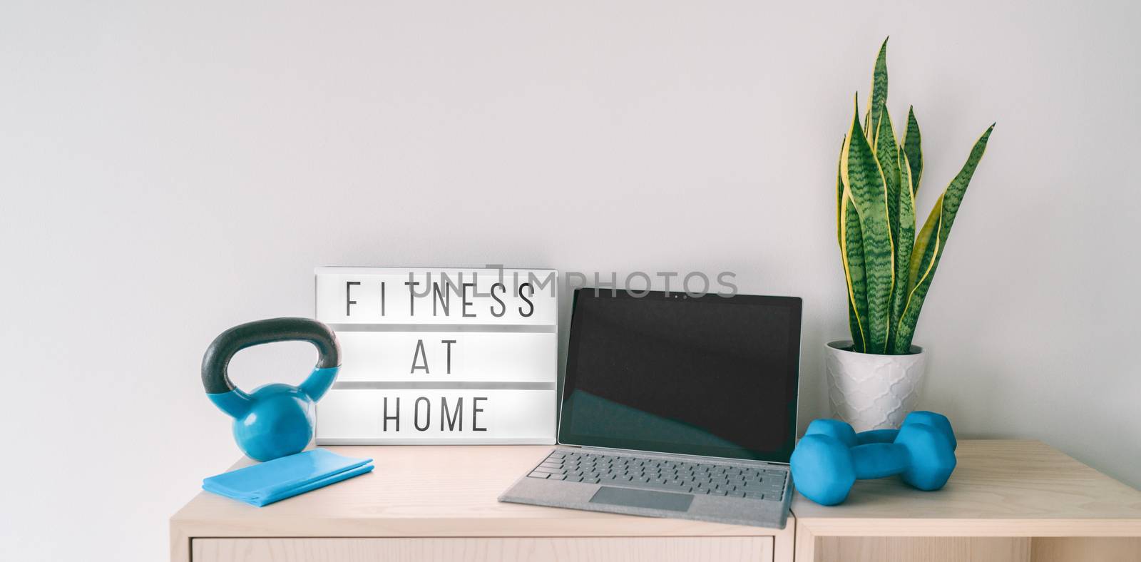 Fitness at home online exercise class on computer laptop with training weights and resistance band. Coronavirus COVID-19 Social distancing sign lightbox banner staying indoor while gyms are closed.