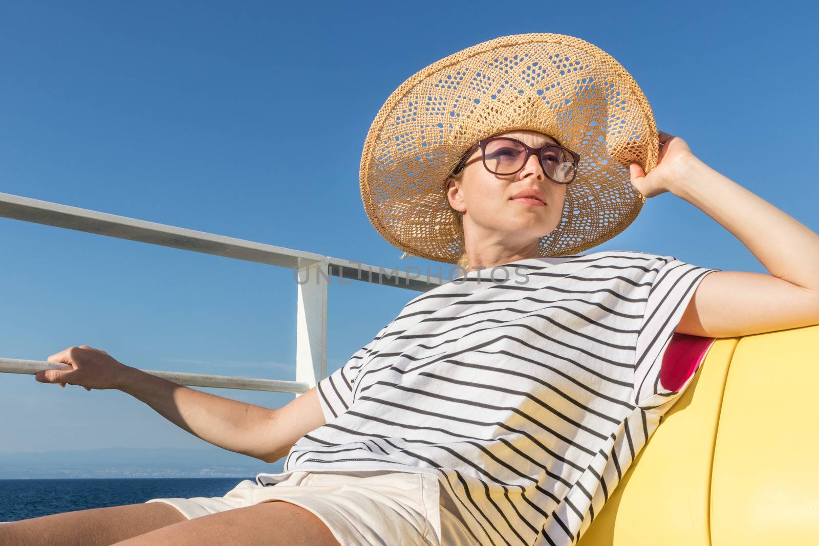 Beautiful, romantic blonde woman taking selfie self portrait photo on summer vacations traveling by cruse ship ferry boat. by kasto