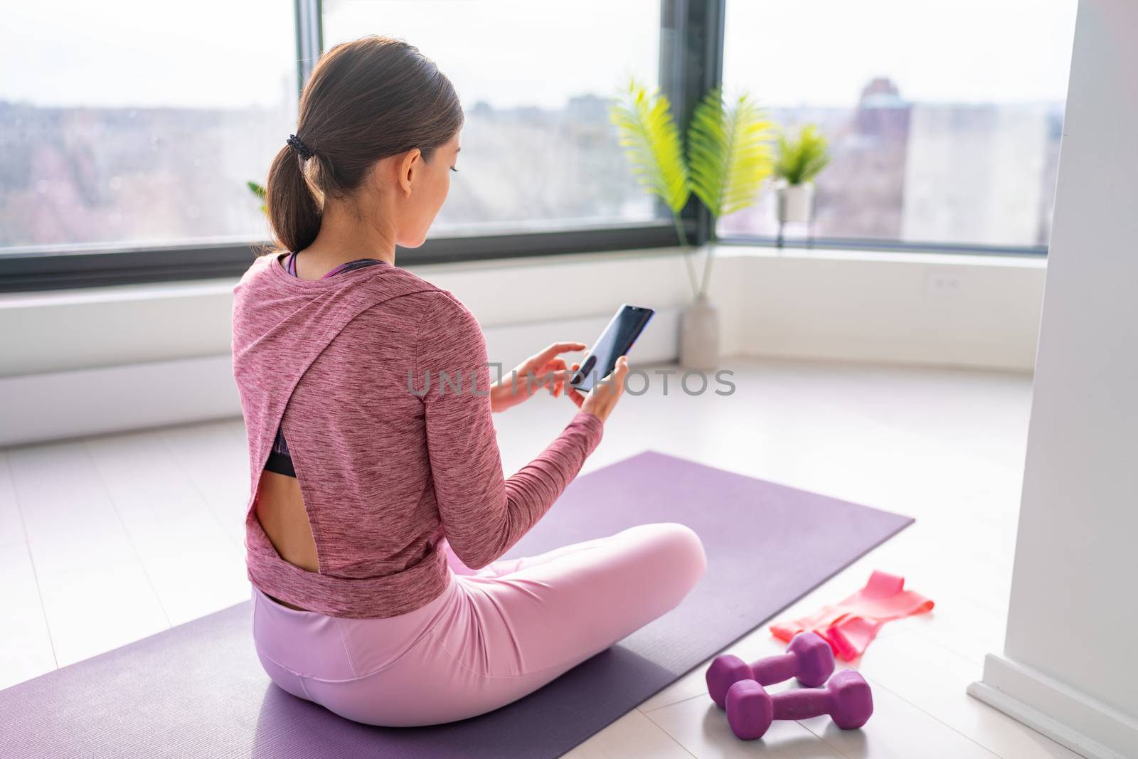 Exercise staying home woman watching fitness videos online on mobile phone yoga workout live streaming influencer fit girl, working out in living room of apartment house.