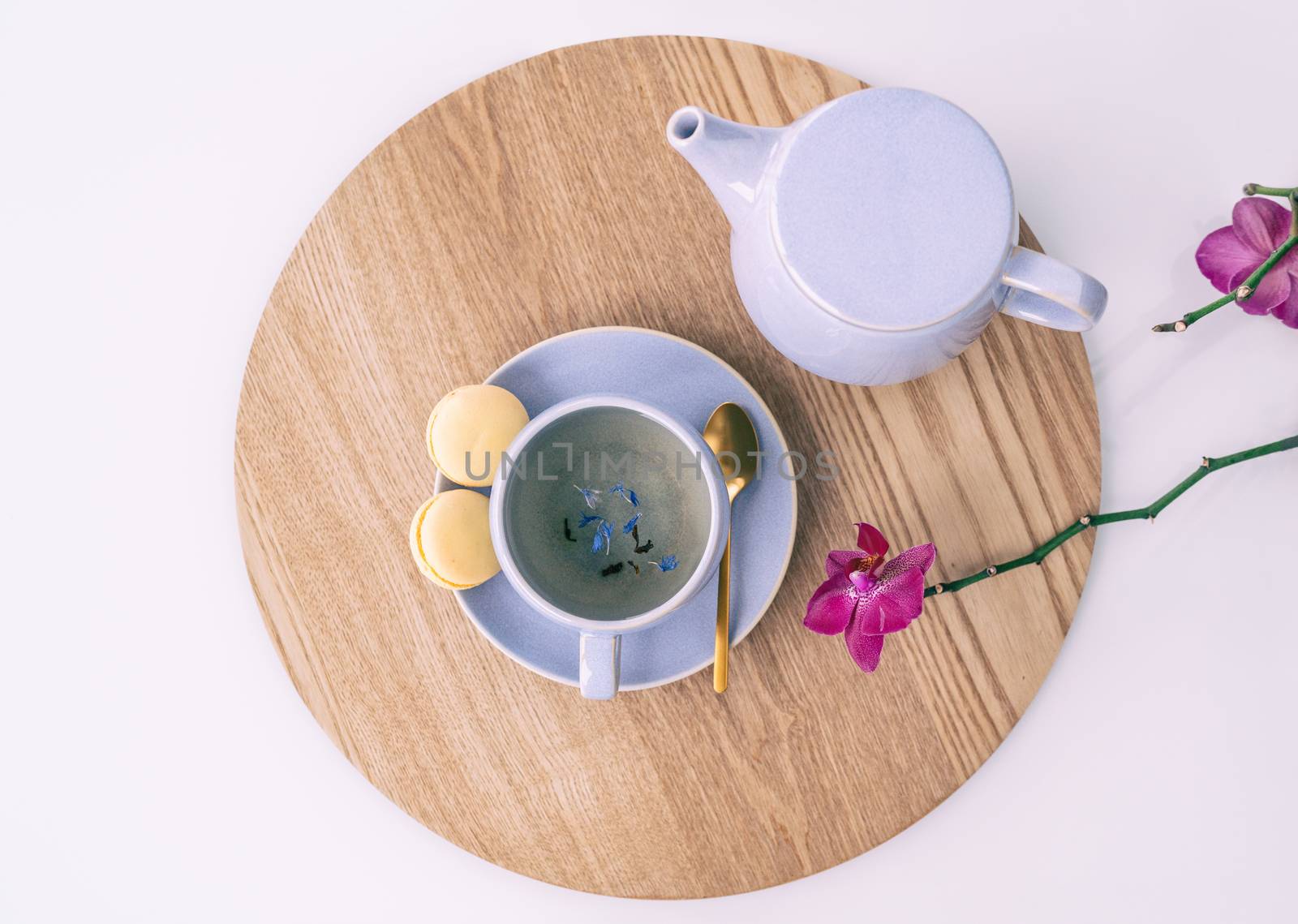 Tea cup earl grey british black tea with teapot and sweet lemon macarons, tabletop serving food drinking at home. with purple lilac leaves and orchids.