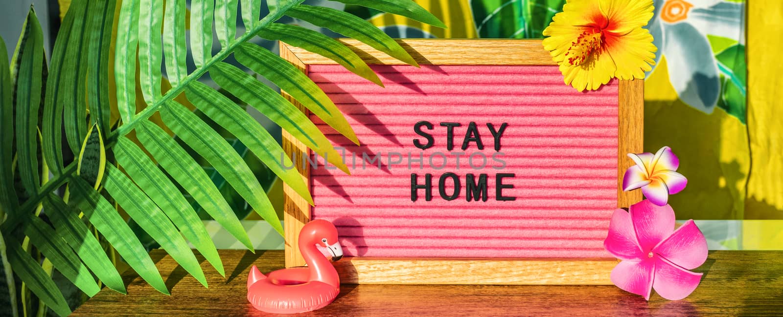 STAY HOME sign for summer vacation plans during COVID-19 travel ban. Tropical background with palm leaves, flowers, flamingo pool float by Maridav