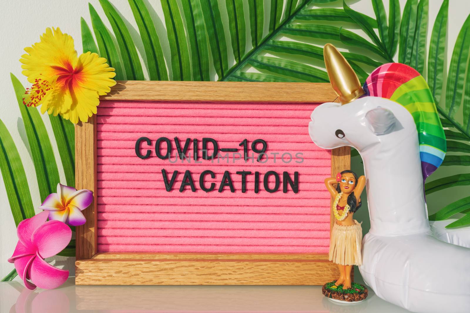 COVID-19 vacation at home pink funny sign for coronavirus travel restrictions this summer. Swimming pool toy float, hula dancer for tropical theme holidays in the backyard.