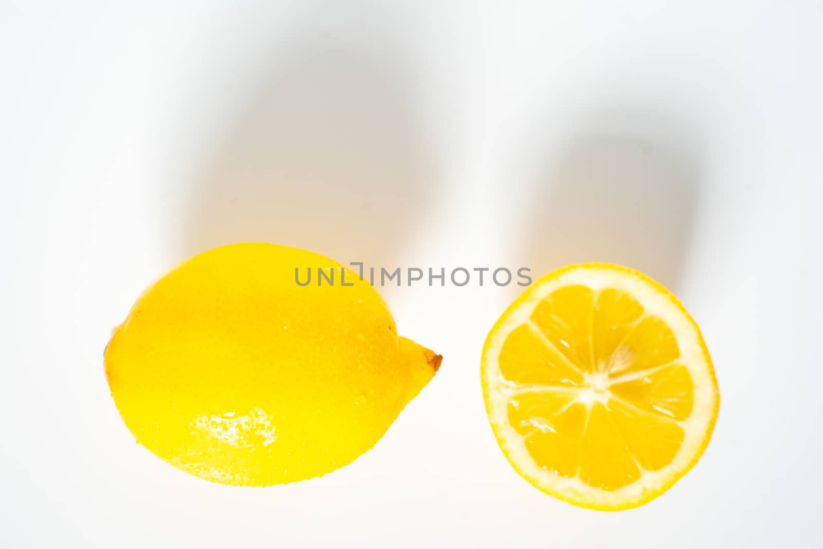 A whole lemon and a half against a plain white background