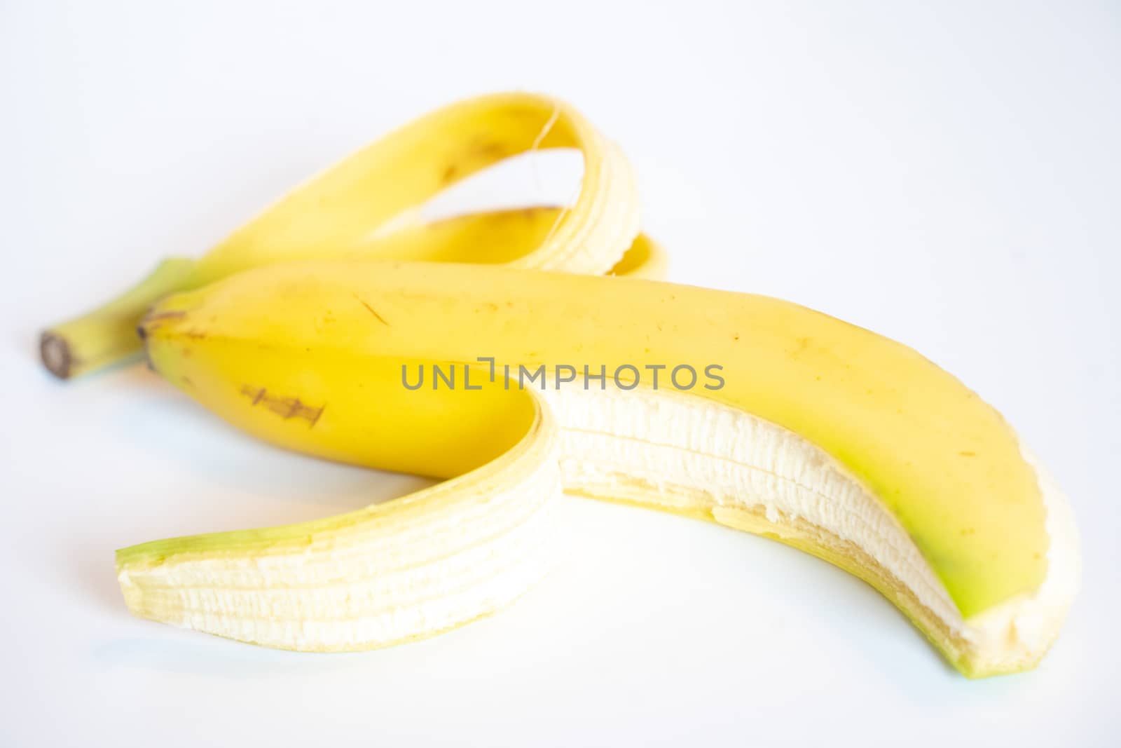 A Whole banana with the skin peeled back against a plain white background