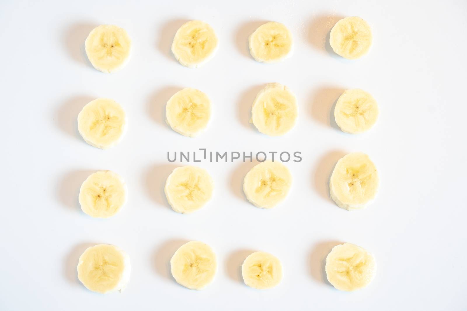 Slices of banana in a square pattern against a plain white background
