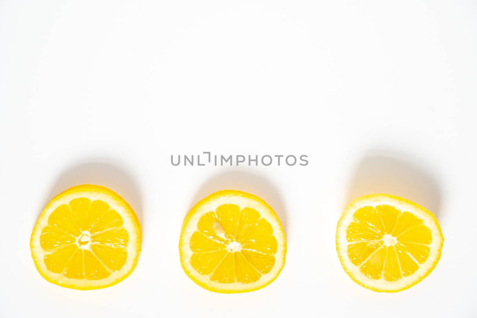 Three slices of lemon in a row against a plain white background