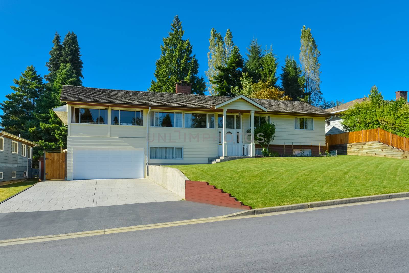 Expanded family house with wide garage, concrete driveway and mowed lawn on the front yard