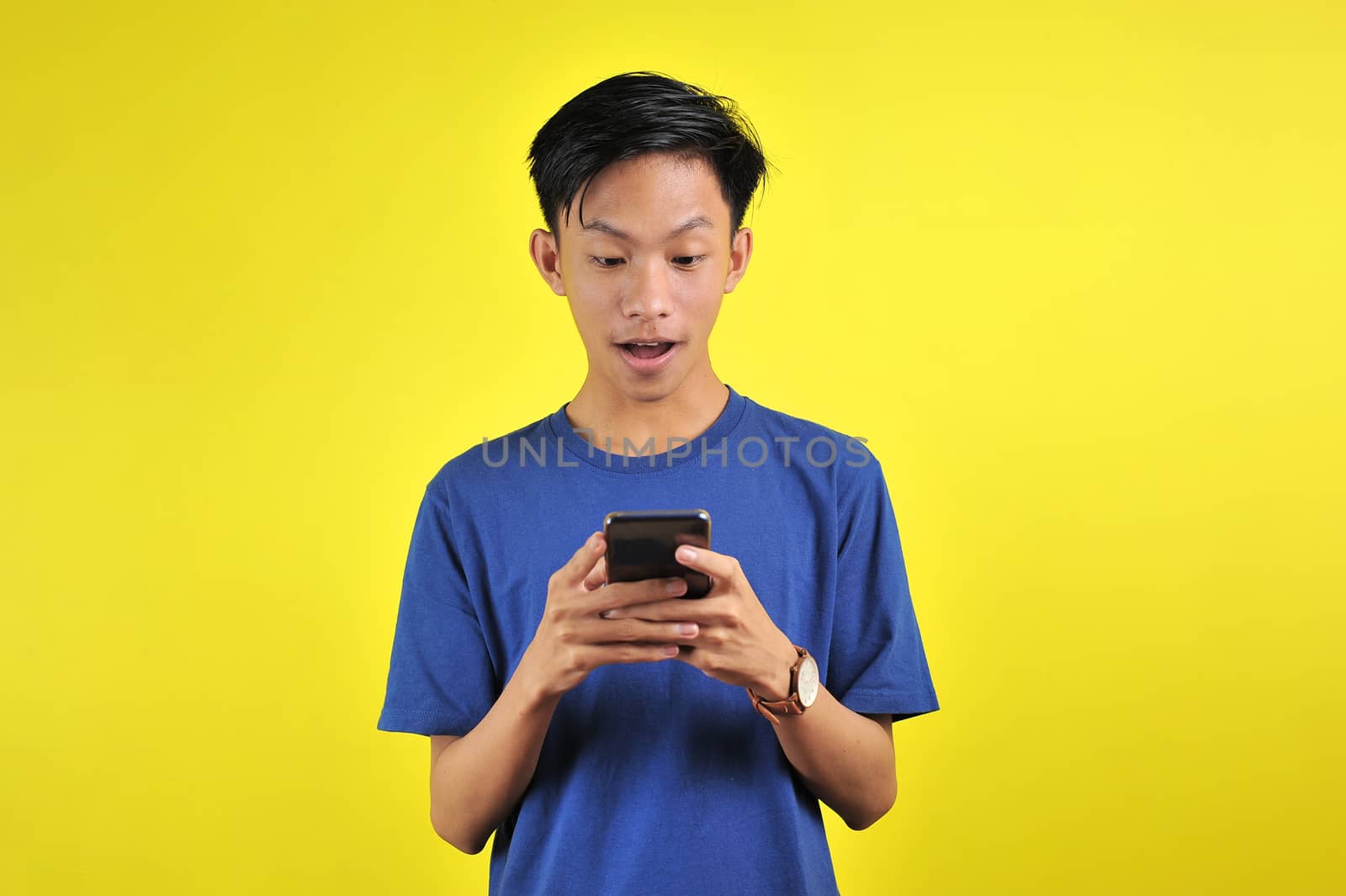 Shocked face of Asian man in white shirt looking at phone screen by heruan1507