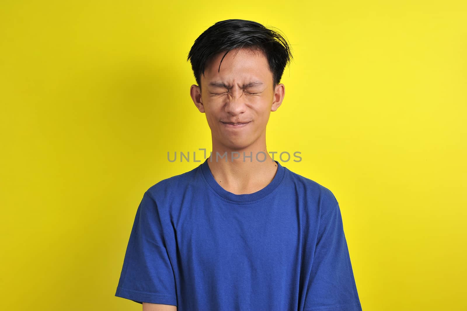 Portrait of young Asian man close his eyes, isolated on yellow background
