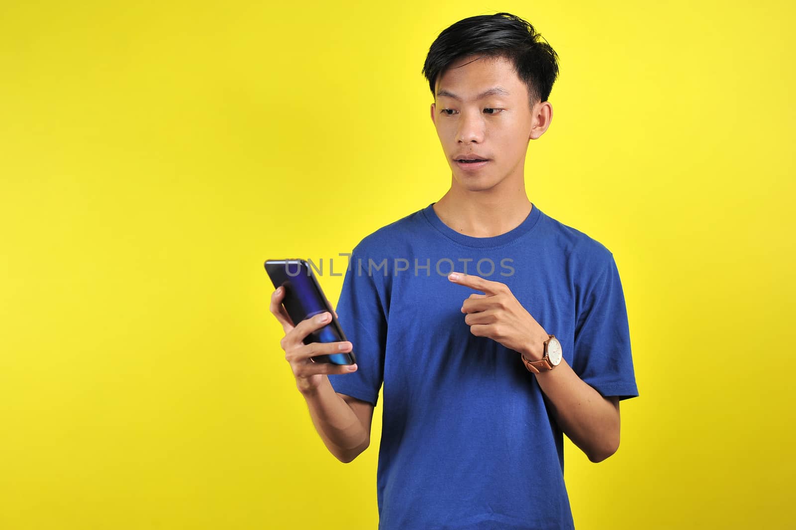 Shocked face of Asian man in white shirt looking at phone screen by heruan1507