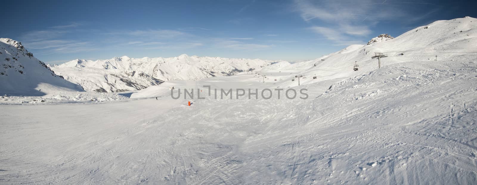 View down a piste with skiers and mountains