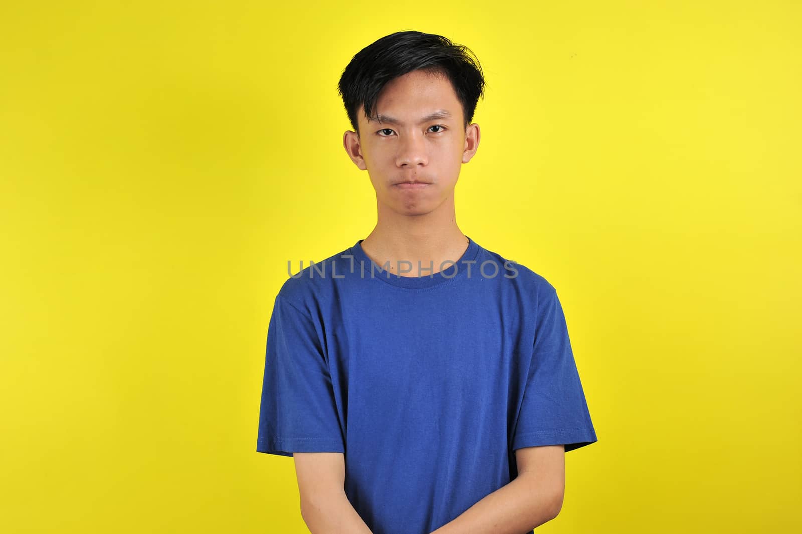 Portrait of young Asian man close mouth gesture, isolated on  yellow