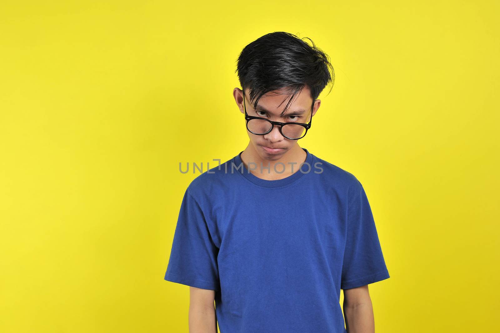 Feeling bored, Young Asian man wearing glasses, isolated on yellow background