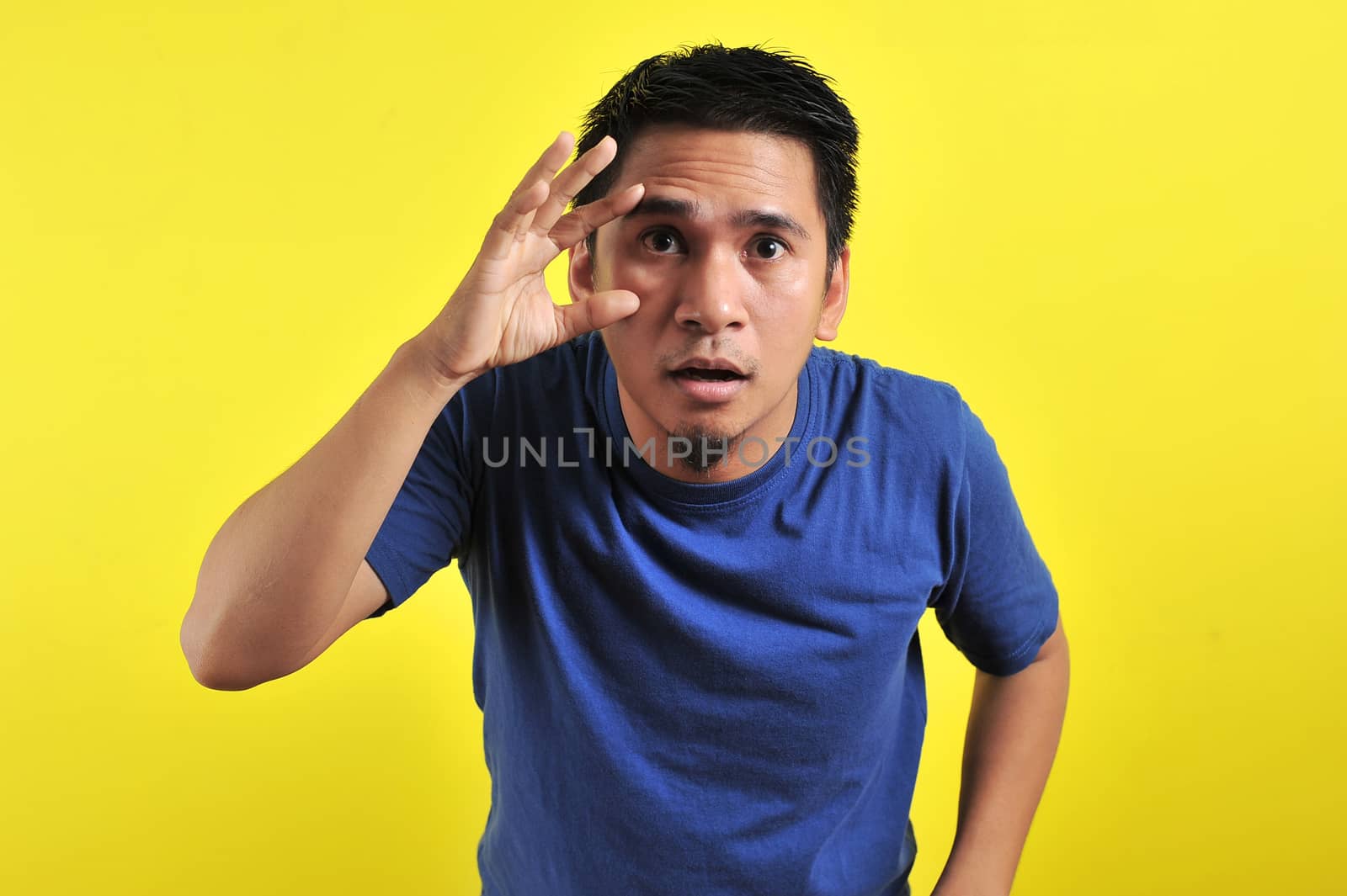 Portrait of Young Asian man open his eyes, isolated on yellow background