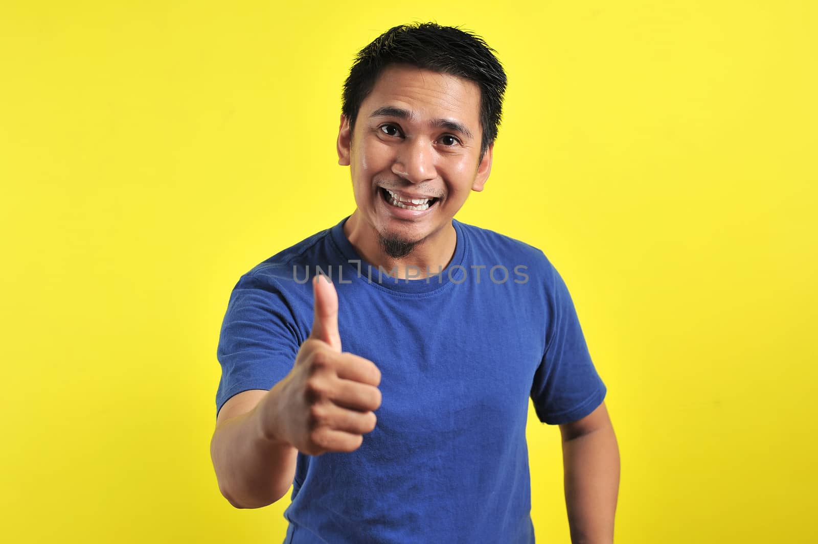 Portrait of young Asian man laughing with showing thumbs up at camera by heruan1507