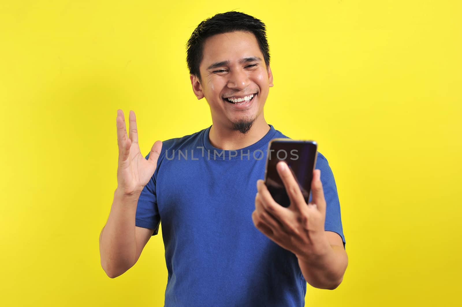 Happy young good looking Asian man smiling using cellphone by heruan1507