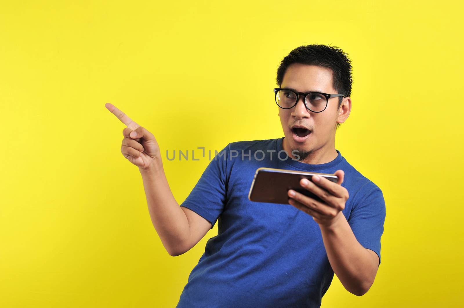 Happy young Asian man shocking using smartphone looking at blank area by heruan1507