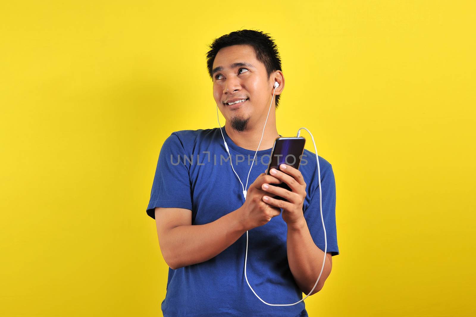 Asian man in casual blue t-shirt wearing headset listening to music by heruan1507