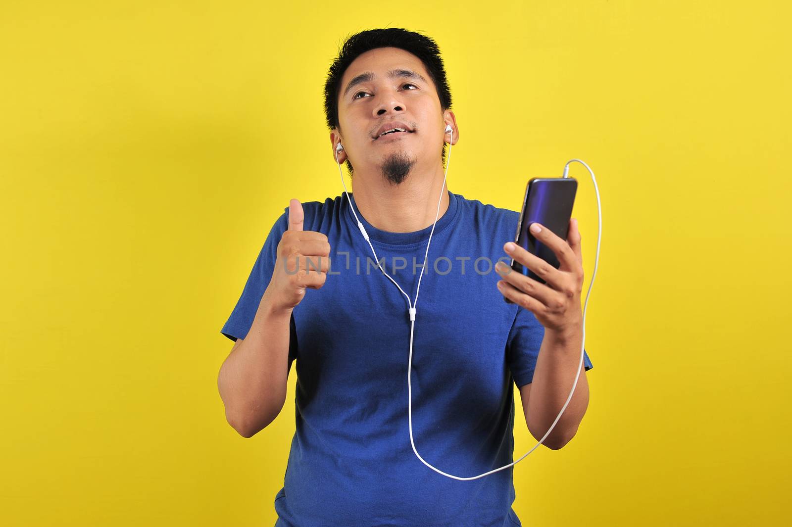 Asian man in casual blue t-shirt wearing headset listening to music by heruan1507